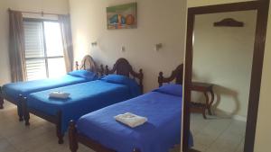 1 dormitorio con 3 camas con sábanas azules y espejo en Hotel Confort, en Santiago del Estero