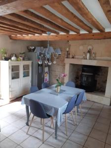een keuken met een tafel met blauwe stoelen en een open haard bij L'auberge mondevillaise in Mondeville