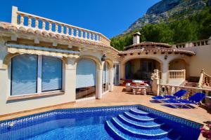 een huis met een zwembad en blauwe stoelen bij Don Quijote Studio SE in Denia