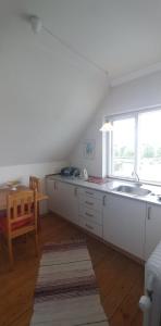 a white kitchen with a sink and a table at My Bureau Apartment in Korsør