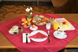 a table with a red table cloth with breakfast food on it at Hotel Wahlmüller in Sattledt