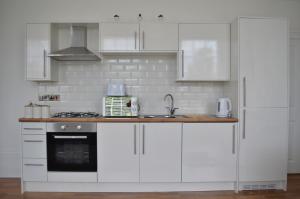 una cocina con armarios blancos y fregadero en Apartment 4 Hamilton Square, en Birkenhead
