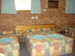 a hotel room with two beds and two chairs at Colonial Motor Lodge Scone in Scone