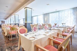 a restaurant with white tables and chairs and windows at Grupotel Parc Natural & Spa in Playa de Muro