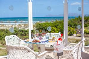 a table with a plate of food and wine glasses on the beach at Grupotel Parc Natural & Spa in Playa de Muro