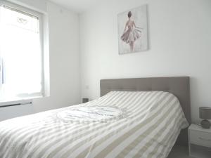 ein Bett in einem weißen Schlafzimmer mit einem Bild an der Wand in der Unterkunft Gîte Parislande proche de Disneyland réservé exclusivement aux familles avec enfants in Saint-Germain-sur-Morin