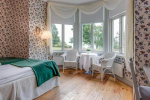 a bedroom with a table and chairs and windows at Hotel Bellevue in Hjo +70 photos