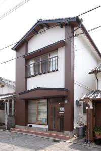 Maison blanche et marron avec 2 balcons dans l'établissement ゲストハウス たまのや, à Hyuga