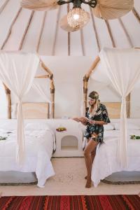 a woman is standing between two beds in a tent at Hotel Okaan in Chichén-Itzá