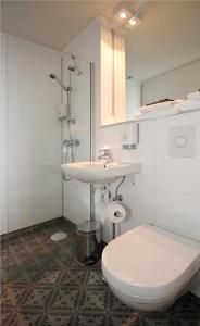 a white bathroom with a toilet and a sink at Sentrum Hotel in Nordfjordeid