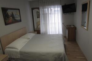 ein Schlafzimmer mit einem großen Bett und einem TV in der Unterkunft Salku Serviced Rooms in Tirana