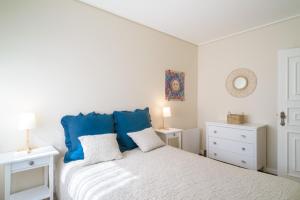 um quarto branco com uma cama com almofadas azuis em APA 12 em Espinho