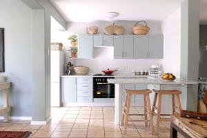 a kitchen with white cabinets and a table and stools at Villa Gardenia One Bedroom in Ballito