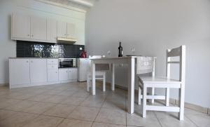 a kitchen with white cabinets and a table and chairs at Nostos Beachfront Apartments & Studios in Agios Ioannis