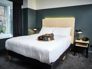 une chambre d'hôtel avec un lit avec un sac dans l'établissement The 1852 Hotel - Self Check-in, à Belfast