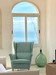 a blue chair and a vase in front of a window at Sky House Amalfi Coast in Scala