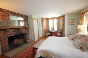 1 dormitorio con 1 cama y chimenea en Highland Lake Inn en Andover