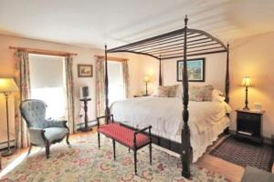 a bedroom with a large bed and a chair at Highland Lake Inn in Andover