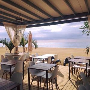 un restaurante con mesas y sillas en la playa en Casa Tomas, en Sant Vicenç de Montalt