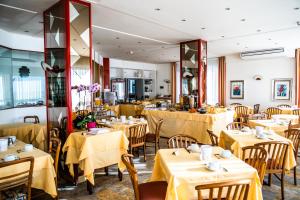 ein Restaurant mit Tischen und Stühlen mit gelben Tischdecken in der Unterkunft Hotel West End in Alassio