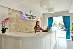 a woman sitting at a counter with a laptop at Summer Garden Suites Beach Hotel in Bitez