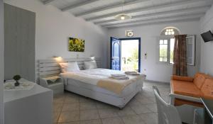 a bedroom with a large white bed and a table at Nostos Beachfront Apartments & Studios in Agios Ioannis