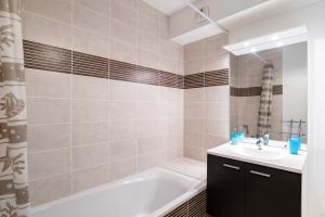 ein Badezimmer mit einer weißen Badewanne und einem Waschbecken in der Unterkunft CityCosy Strasbourg - Neudorf Garden Bucarest in Straßburg