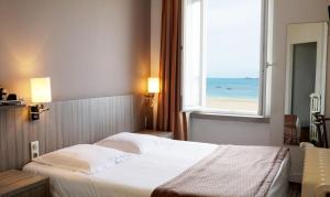 a bedroom with a bed with a view of the ocean at Hôtel Le Jersey in Saint Malo
