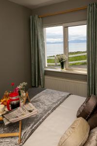 a bedroom with a bed with a window and a table at Ballyheigue Cliff Side and Sea View Apartment in Ballyheigue