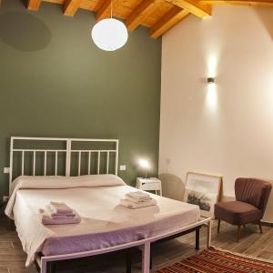 a bedroom with a large bed and a chair at EcoAgriturismo Notti Stellate Etna Mare in Mascali