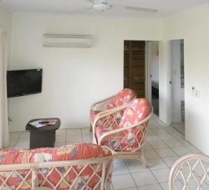 sala de estar con 2 sillas y sofá en Tradewinds McLeod Holiday Apartments, en Cairns