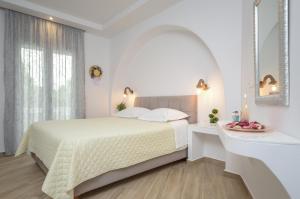 a white bedroom with a bed and a mirror at Sun Beach Hotel in Naxos Chora