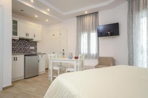 a white bedroom with a table and a kitchen at Sun Beach Hotel in Naxos Chora