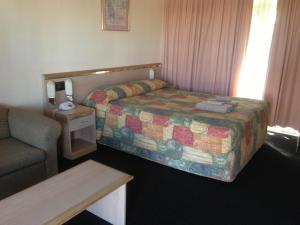 Habitación de hotel con cama y sofá en Colonial Motor Lodge Scone en Scone