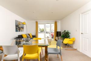 a living room with a dining room table and yellow chairs at Hertford Serviced Apartments by Payman Club in Hertford