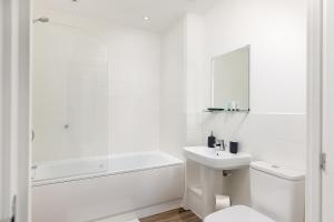 a white bathroom with a tub sink and a toilet at Hertford Serviced Apartments by Payman Club in Hertford +41 photos