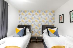 a bedroom with two beds and a accent wall at Hertford Serviced Apartments by Payman Club in Hertford