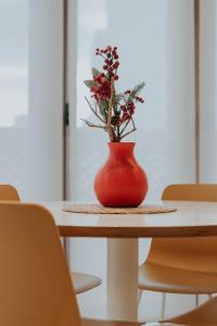 a red vase with flowers sitting on a table at Apartamento de Esther y Javi in Elche