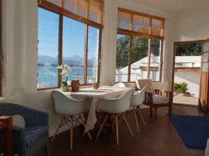 una sala da pranzo con tavolo, sedie e finestre di Westbank Private Beach Villa, 4 Bedrooms, Private pool, on the Beach! a Gordonʼs Bay