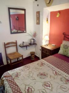 a bedroom with a bed and a mirror and a chair at Casa La Rosa in Almedinilla