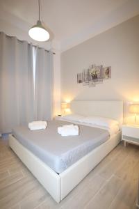 a white bedroom with two beds and a lamp at Unique luxury apartment and rooms in Rome