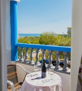 a table with wine glasses on a balcony with the ocean at Poseidon Apartment in Archangelos