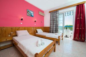 two beds in a room with a pink wall at Poseidon Apartment in Archangelos