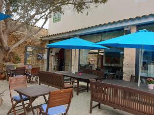 eine Terrasse mit Tischen, Stühlen und blauen Sonnenschirmen in der Unterkunft Hotel Segles - Turismo de Interior in Campos