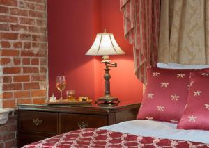 a bedroom with a red bedspread and a lamp on the wall at Napa River Inn in Napa