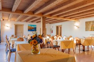 een eetkamer met tafels en stoelen en een vaas met bloemen bij Casa Moresc in Spiazzo