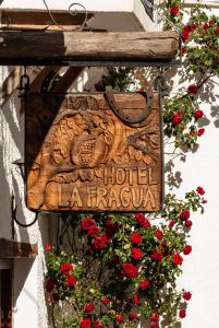 ein Schild an der Seite eines Gebäudes mit roten Blumen in der Unterkunft Hotel La Fragua I in Trevélez