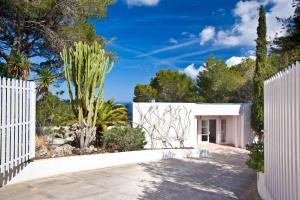 a white fence in front of a house with trees at VILLA CAN HERMANOS: Wifi gratis, piscina privada y vistas al mar in Sant Josep de Sa Talaia