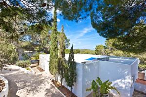 サン・ジョセップ・デ・サ・タライアにあるVILLA CAN HERMANOS: Wifi gratis, piscina privada y vistas al marの木と柵の白い家