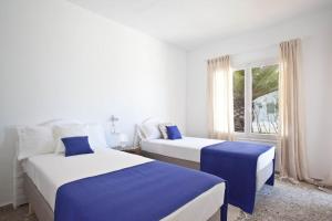 two beds in a white room with a window at VILLA CAN HERMANOS: Wifi gratis, piscina privada y vistas al mar in Sant Josep de Sa Talaia